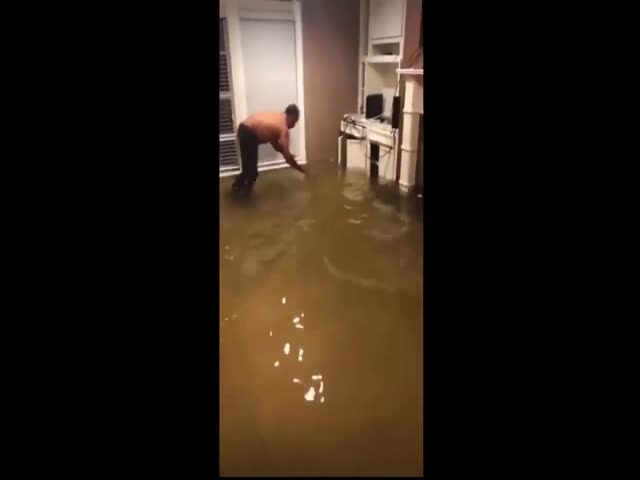 Мужчина ловит рыбу в затопленном доме